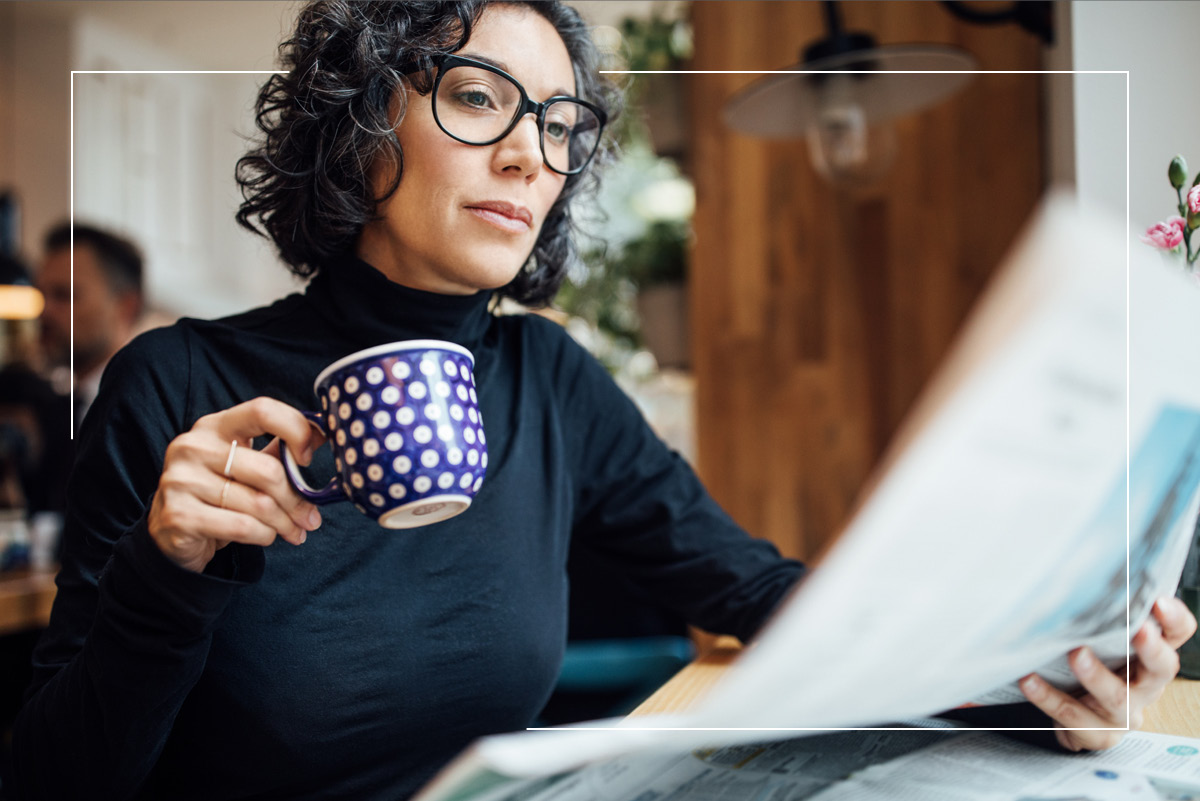 woman drinking coffee and reading newspaper